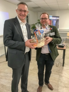 Wirtschaftsförderer Thomas Zacharias (rechts) überreicht Sonoco Geschäftsführer Bernd Rost einen Korb mit typischen Troisdorfer Produkten